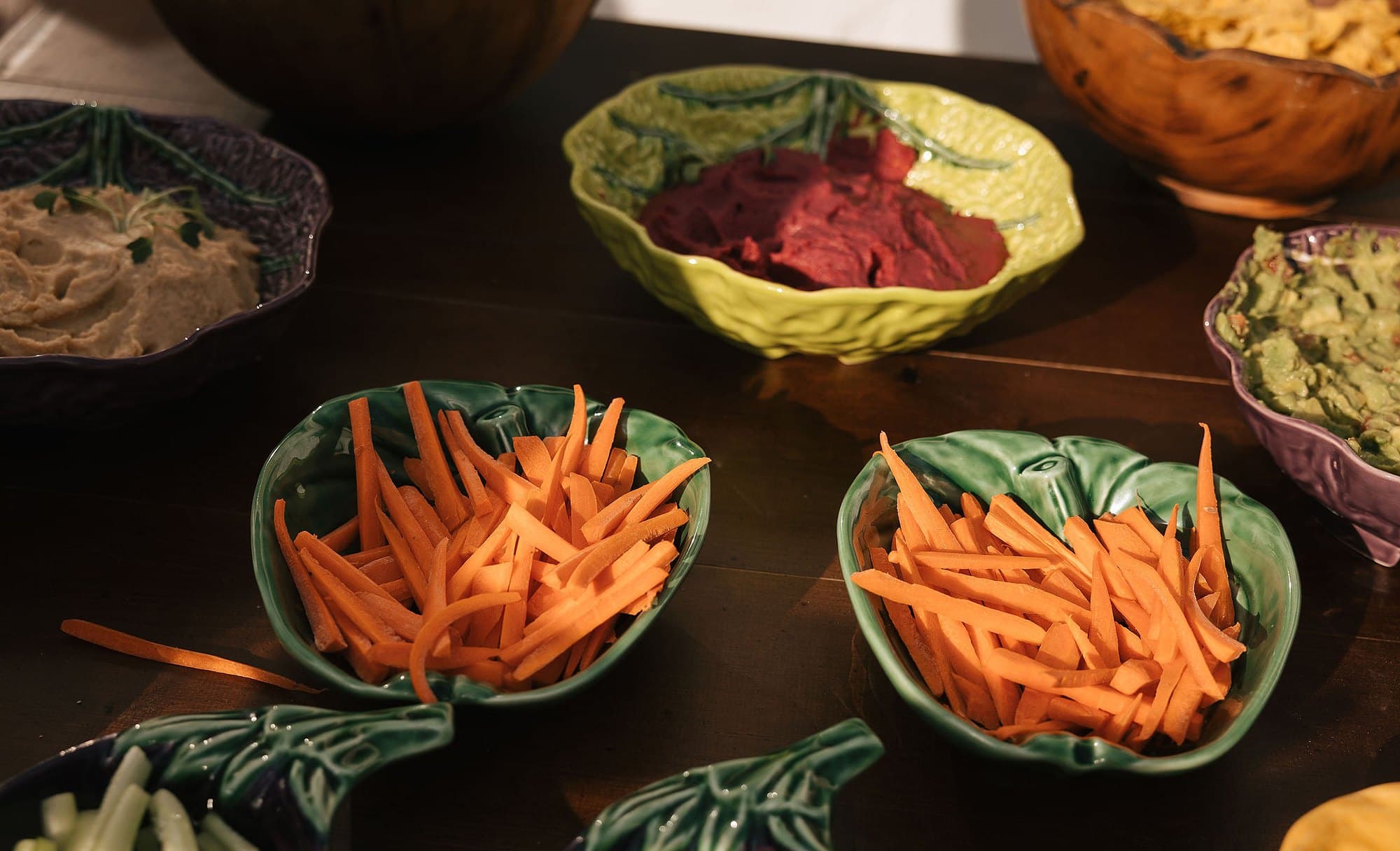 Palitos de cenoura e pepino com pastas de beterraba e de legumes, em taças de cerâmica em forma de folha.